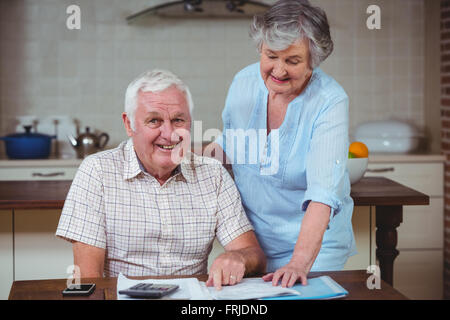 Lächelnder senior Mann mit Frau bei der Berechnung der Rechnungen Stockfoto