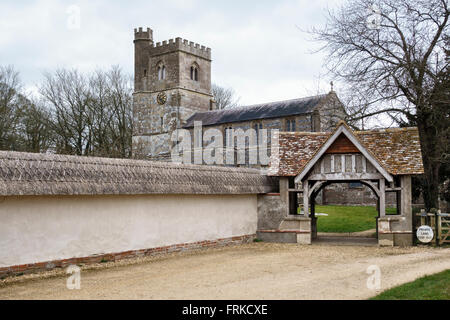 All Saints Church, Enford, Wiltshire, UK. Ein 12c Norman Feuerstein Kirche mit einer feinen strohgedeckten Cob Mauer rund um den Kirchhof Stockfoto