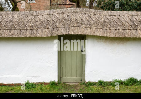 All Saints Church, Enford, Wiltshire, UK. Es gibt eine feine traditionellen strohgedeckten Cob Wand rund um den Kirchhof Stockfoto