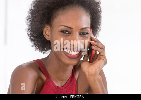Nahaufnahme eines lächelnden Frau auf ihrem Handy vor einem weißen Hintergrund Stockfoto