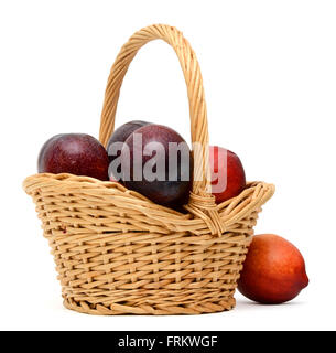 Ein Korb mit Pflaumen und Pfirsiche auf weißem Hintergrund Stockfoto