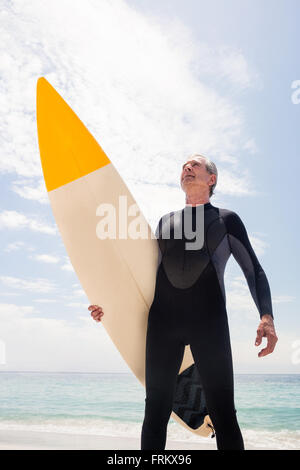 Senior Woman im Neoprenanzug hält ein Surfbrett Stockfoto