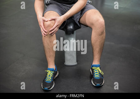 Mann mit einem verletzten Knie sitzen im Fitness-Studio Stockfoto