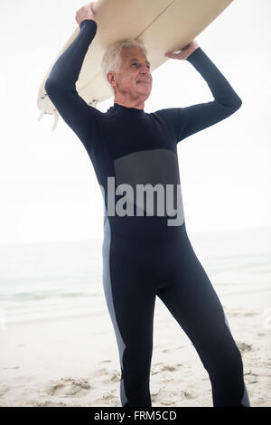 Senior woman ein Surfbrett über den Kopf halten Stockfoto