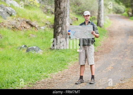 Junger Mann lesen Karte auf Wanderweg im Wald Stockfoto
