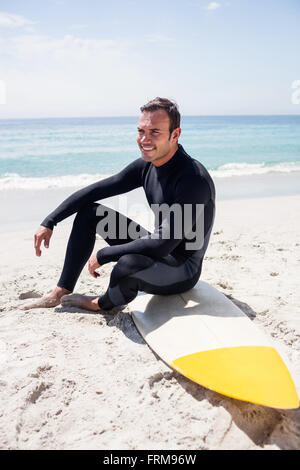 Glückliche Surfer im Neoprenanzug mit Surfbrett am Strand sitzen Stockfoto