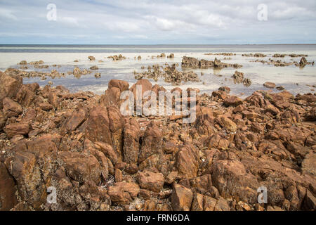 Felsenstrand, hellen Sand im seichten Wasser, Horizont, etwas dunstig Wetter Stockfoto