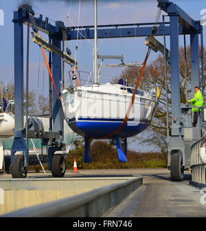 Yacht wird nach Winterlagerung wieder ins Wasser gehisst auf dem harten Stand in Premier Chichester Marina - Chichester, West Sussex, UK Stockfoto