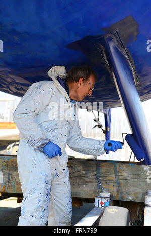 Der Bootsbesitzer, der seine zweikegelige Yacht mit einer Walze (Seewegenprägung) abkeucht und sich auf die neue Segelsaison vorbereitet. West Sussex, Großbritannien Stockfoto