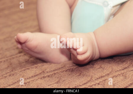 Neugeborenes Baby Füße auf gestrickte Hintergrund, Mutters Tag-Konzept Stockfoto