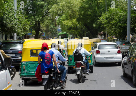 Paar am Motorrad im Verkehr mit Tuk Tuks, Delhi, Indien Stockfoto