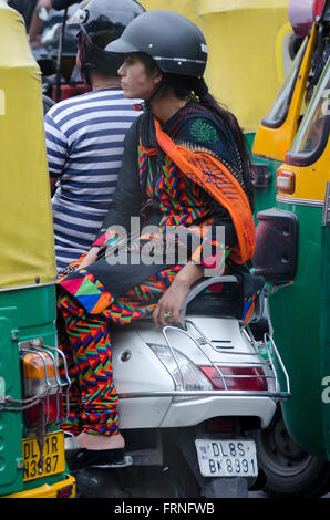 Paar auf Motorroller im Verkehr mit Tuk Tuks, Delhi, Indien Stockfoto