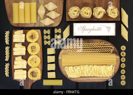 Große getrocknete Pasta Auswahl an Speisen auf Ahorn-Boards mit alten Spaghetti Schild über dunklem Holz. Stockfoto