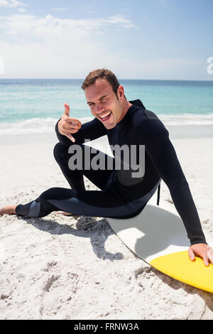 Glückliche Surfer im Neoprenanzug mit Surfbrett am Strand sitzen Stockfoto