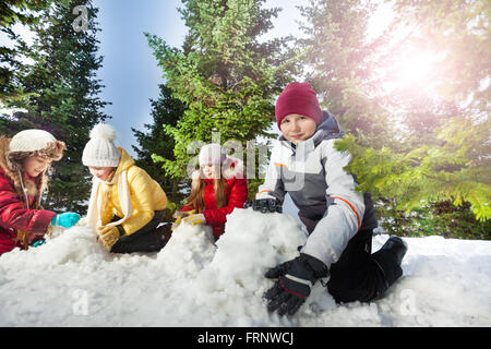 Vier Kinder Schneemann im schönen Wald Stockfoto