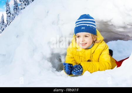 Kleiner Junge in gelben Crawl durch Schnee tunnel Stockfoto