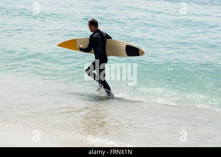 Surfer am Strand mit einem Surfbrett Stockfoto