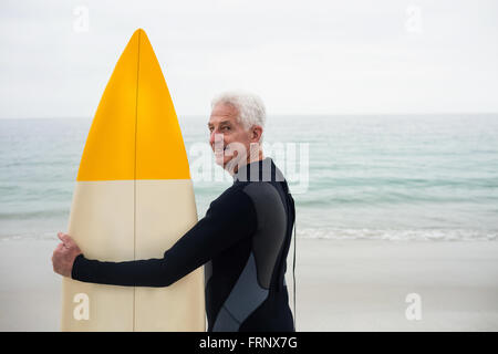 Happy senior woman im Neoprenanzug hält ein Surfbrett Stockfoto