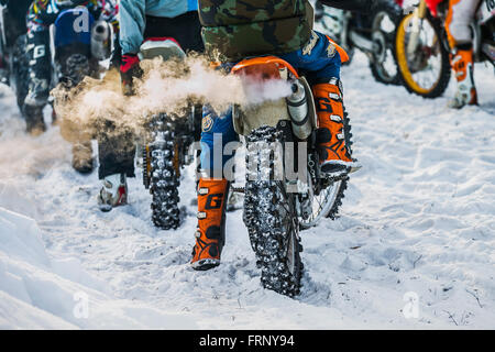 Closeup Fahrer auf Motorrad Auspuff Rauch während Cup Winter Motocross Rennstart vorbereiten Stockfoto