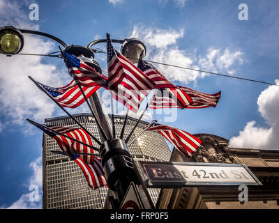 East 42nd St Zeichen und Gruppe von amerikanischen Flaggen auf Laternenpfahl, New York City, USA. Stockfoto