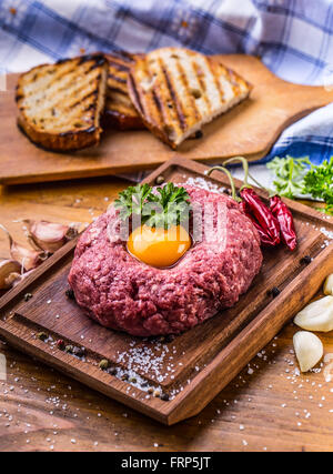 Rohes Rindfleisch. Lecker Steak Tartare. Klassische Tatar auf Holzbrett. Zutaten: Rohes Rindfleisch Fleisch Salz Pfeffer Ei Knoblauch chili Stockfoto