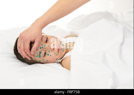 kranke Kind im Bett hat das Virus auf Haut, Mutters Hand berührt die Stirn Stockfoto