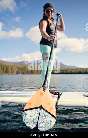 Eine junge Frau Paddel Boards auf Daicy Teich im Maines Baxter State Park. Stockfoto