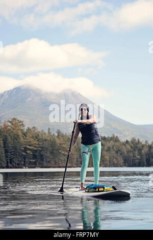 Eine junge Frau Paddel Boards auf Daicy Teich im Maines Baxter State Park. Stockfoto