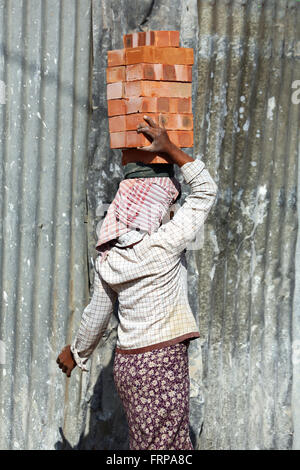 Frau, die Ziegel auf dem Kopf auf einer Baustelle in Amarapura, Mandalay, Myanmar (Burma) Stockfoto