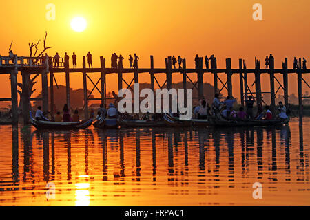 Menschen, die über die U Bein Brücke über den Taungthaman-See bei Sonnenuntergang in Amarapura, Mandalay, Myanmar (Burma) Stockfoto