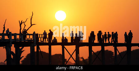 Menschen, die über die U Bein Brücke über den Taungthaman-See bei Sonnenuntergang in Amarapura, Mandalay, Myanmar (Burma) Stockfoto