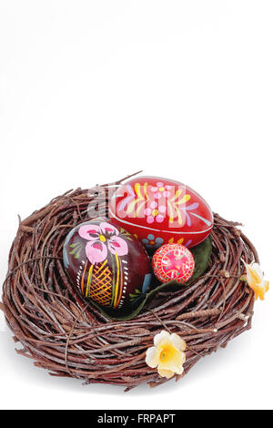 handbemalte Ostereier im Nest auf weißen Tisch Stockfoto