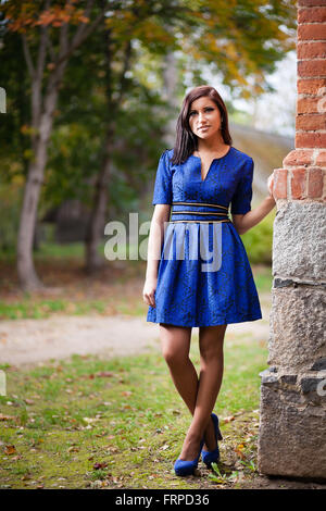 Brünette Mädchen im blauen Kleid in der Nähe einer Mauer. Stockfoto