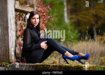 Brünette Mädchen sitzen auf überwucherten Treppen. Stockfoto