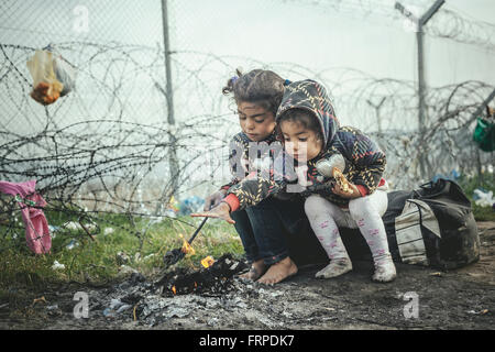 Idomeni Flüchtlingslager an der Grenze Griechenland Mazedonien, zwei kleine Mädchen wärmen sich an einem Lagerfeuer, Idomeni, Zentral-Makedonien Stockfoto