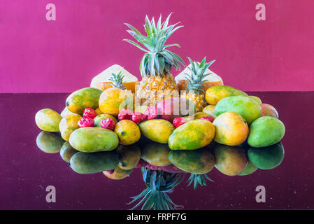 Eine Auswahl von bekannten und berühmten Markt frischen tropischen Mauritius Früchten auf einem lila Glastisch im Magenta Hintergrund Stockfoto