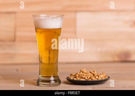 Kaltes Bier mit gerösteten Erdnüssen auf Holztisch, Still-Life-style Stockfoto