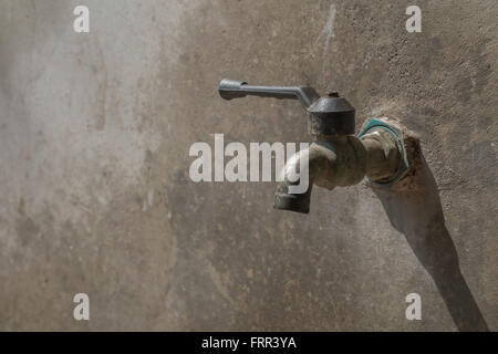 Alter Wasserhahn auf Betonwand, speichern das Wasserkonzept Stockfoto