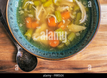 Selbstgemachte Hühnersuppe in einem türkis Schüssel mit antiken Löffel. Stockfoto