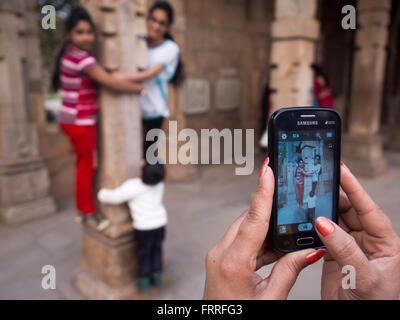 Frau fotografieren Freunde mit mobilen Kamera bei Qutub Minar, New Delhi, Indien. Stockfoto