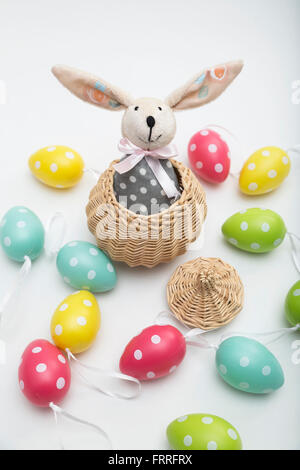 Spielzeug-Osterhase im Weidenkorb mit bunt gefärbten Eiern Stockfoto