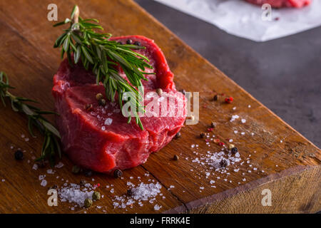 Steak. Rohes Rindfleischsteak. Frisches rohes Rindfleisch Rumpsteak in Scheiben geschnitten oder ganz bereit für BBQ oder Grill. Kraut - Rosmarin-Dekoration. Stockfoto