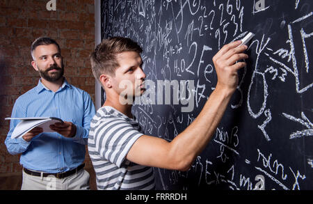 Lehrer und Schüler, die an große Tafel mit mathematischen schreiben Stockfoto