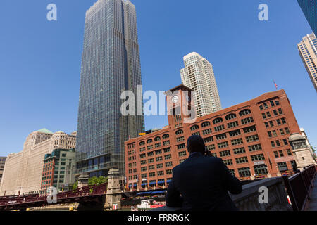 Skyline-Blick aus dem Riverwalk auf dem Chicago River mit einem Mann am Telefon Silhouette in Chicago, Illinois, USA Stockfoto