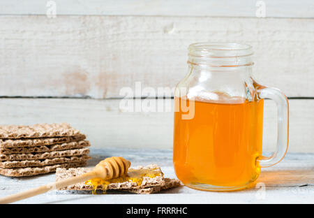 Honig mit einem Schöpflöffel und Knäckebrot auf hölzernen Hintergrund Stockfoto