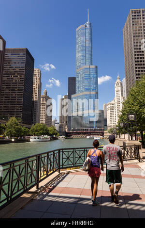 Ein paar Spaziergänge entlang dem Riverwalk auf dem Chicago River mit dem Trump Tower und die Skyline von Chicago, Illinois, USA Stockfoto