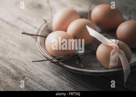 Eiern mit Band und Niederlassungen auf dem Holztisch Stockfoto