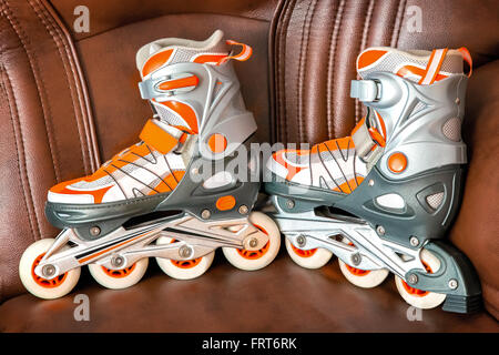 Inline Skates für Frauen auf dem Hintergrund des Sofas. Die Alternative zum passiven Ruhe. Stockfoto