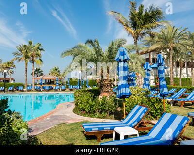 Liegestühlen, Palmen und Pool im tropischen Garten der Luxus Hotel Beach Resort in Dubai, Vereinigte Arabische Emirate Stockfoto