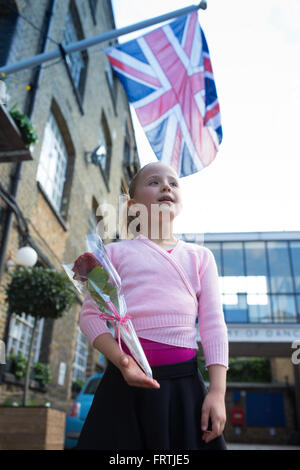 Ein junges Mädchen posiert mit einer roten Rose nach ihrem Grad 1 Ballett Prüfung außerhalb der Royal Academy of Dance in London Stockfoto